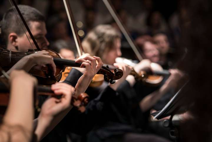 Un orchestre symphonique avec des violonistes au premier plan